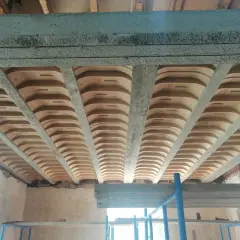 Widok od dołu na strop żelbetowy z pustakami ceramicznymi, tworzący charakterystyczny falisty wzór.