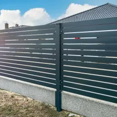 Nowoczesne ogrodzenie z poziomych paneli, osadzone na betonowym cokole. To świetne rozwiązanie, co zamiast podmurówki pod ogrodzenie, zapewniające estetykę i trwałość.