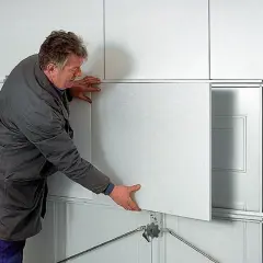 Mężczyzna montuje panel do ocieplenia bramy garażowej.