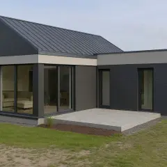 Nowoczesna przybudówka przy domu z dużymi oknami i tarasem.