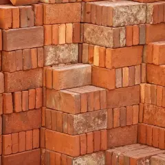 Stosy czerwonych cegieł, każdy budulec waży tyle, że można z nich zbudować solidny mur.