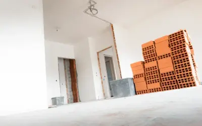 Materiały budowlane i przygotowania do remontu. Stosy pustaków i otwarte przejścia sugerują, jak wyrównać ściany w starym domu.