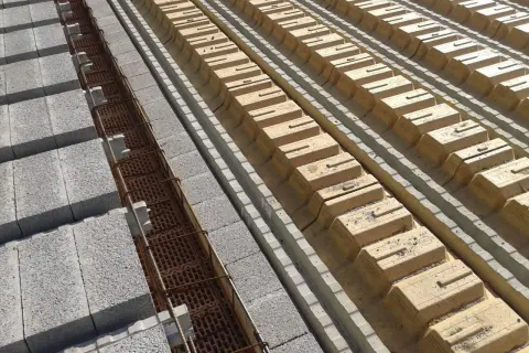 Budowa stropu: betonowe pustaki i zbrojenie w rowkach, obok żółte pustaki szalunkowe. Określanie grubości stropu.