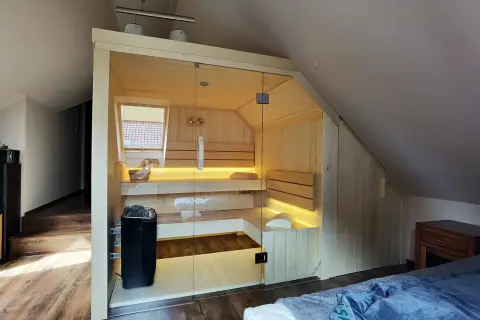 Nowoczesna sauna w domu, z przeszklonymi drzwiami i nastrojowym oświetleniem. Idealne miejsce na relaks po długim dniu.