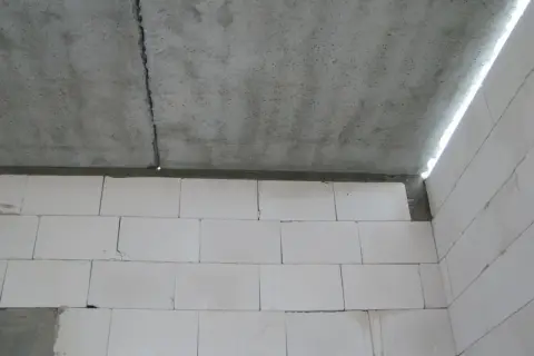 Betonowy strop dz 3 z widocznym pęknięciem, nad ścianą z białych pustaków.