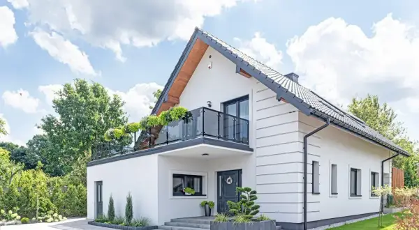 Nowoczesny biały dom z balkonem i zielenią. Idealny przykład, jak mogą wyglądać darmowe projekty domów.