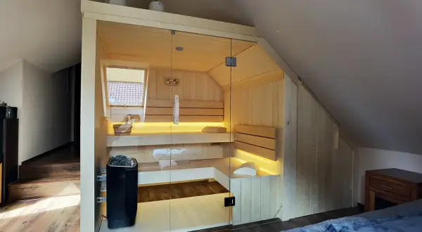 Nowoczesna sauna w domu, z przeszklonymi drzwiami i nastrojowym oświetleniem. Idealne miejsce na relaks po długim dniu.