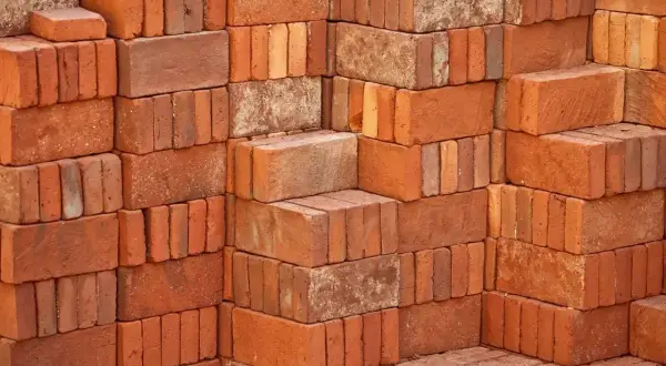 Stosy czerwonych cegieł, każdy budulec waży tyle, że można z nich zbudować solidny mur.