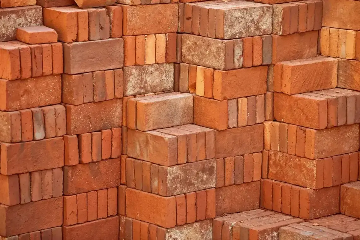 Stosy czerwonych cegieł, każdy budulec waży tyle, że można z nich zbudować solidny mur.