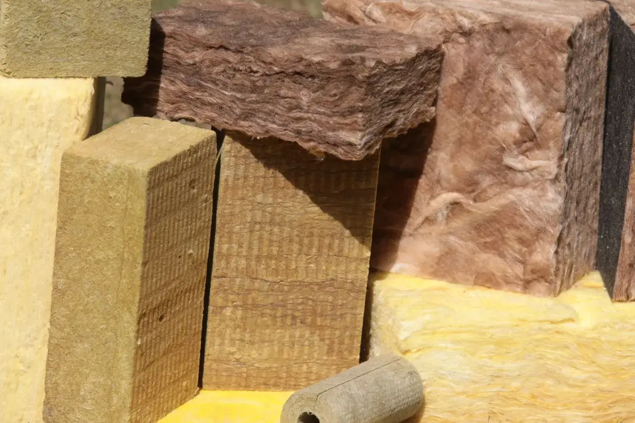 Różne rodzaje wełny mineralnej twardej i miękkiej, w tym żółte i brązowe płyty, gotowe do izolacji.
