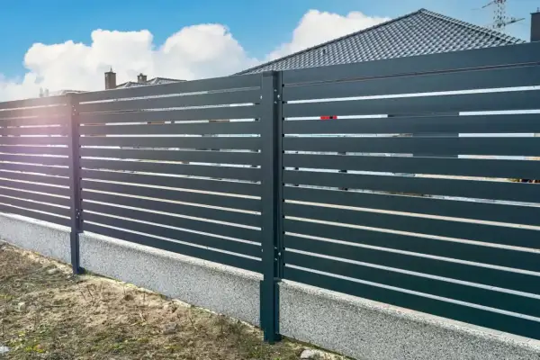 Nowoczesne ogrodzenie z poziomych paneli, osadzone na betonowym cokole. To świetne rozwiązanie, co zamiast podmurówki pod ogrodzenie, zapewniające estetykę i trwałość.