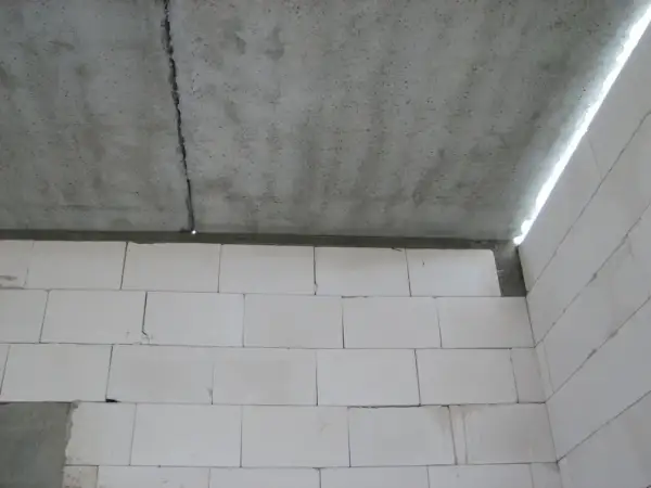 Betonowy strop dz 3 z widocznym pęknięciem, nad ścianą z białych pustaków.